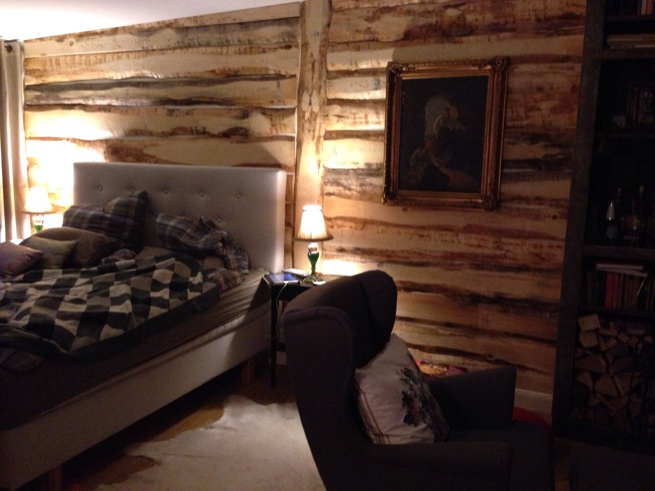 Bett vor rustikaler Holzwand im Schlafzimmer