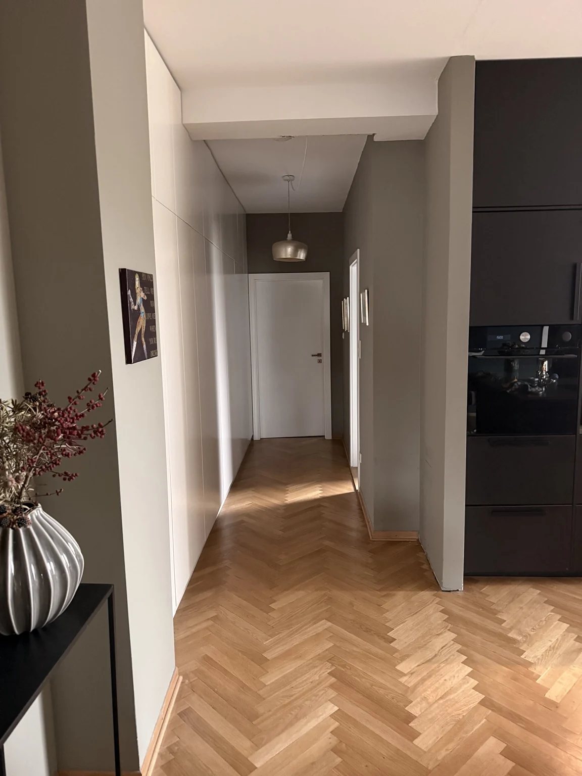 Flur mit weißen Einbauten und Fischgrätparkett